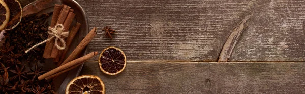 Top view of cinnamon sticks, anise and dried citrus fruit on wooden rustic table, panoramic shot — Stock Photo