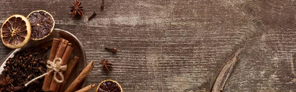 Vista superior de paus de canela, anis e citrinos secos em mesa rústica de madeira com espaço de cópia, tiro panorâmico — Fotografia de Stock