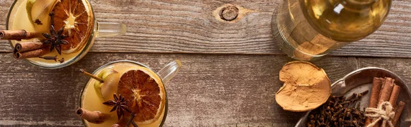 Draufsicht auf warmen Birnenglühwein mit Gewürzen und getrockneten Zitrusfrüchten auf rustikalem Holztisch, Panoramaaufnahme — Stockfoto