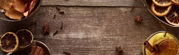 Draufsicht auf warmen Birnenglühwein mit Gewürzen und getrockneten Zitrusfrüchten auf rustikalem Holztisch, Panoramaaufnahme — Stockfoto