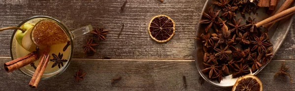 Draufsicht auf warmen Birnenglühwein mit Gewürzen und getrockneten Zitrusfrüchten auf Holztisch, Panoramaaufnahme — Stockfoto