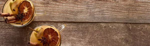 Top view of warm pear mulled wine with spices and dried citrus on wooden table, panoramic shot — Stock Photo