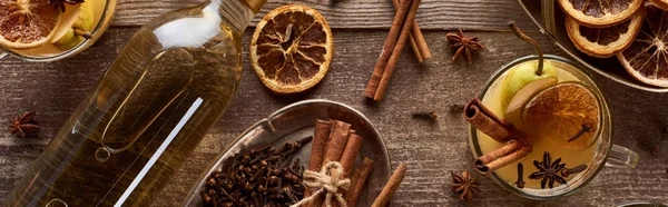 Top view of warm pear mulled wine with spices and dried citrus on wooden table, panoramic shot — Stock Photo