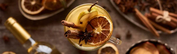 Selective focus of pear mulled wine with spices and dried citrus on wooden table, panoramic shot — Stock Photo