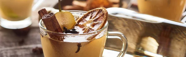 Delicious pear mulled wine with spices and dried citrus on wooden table, panoramic shot — Stock Photo