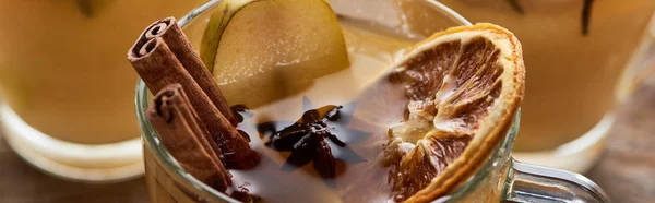 Close up view of pear mulled wine with spices and dried citrus on wooden table, panoramic shot — Stock Photo
