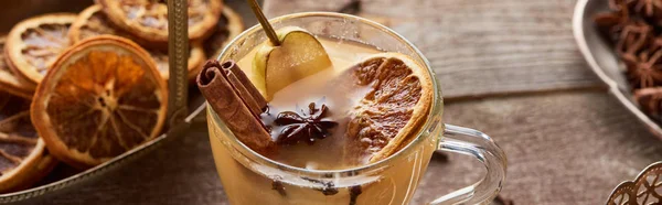 Selective focus of pear mulled wine with spices and dried citrus on wooden table, panoramic shot — Stock Photo