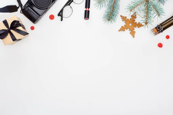 Appareil photo numérique, lunettes, branche de sapin, rouge à lèvres, boîte cadeau, bouteille de champagne, flocon de neige jouet isolé sur blanc — Photo de stock