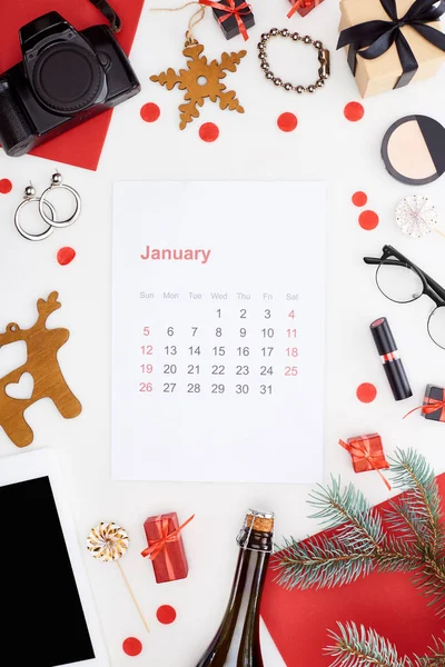 Página de calendário de janeiro, câmera digital, garrafa de champanhe, tablet digital, cosméticos, óculos, ramo de abeto, brincos, papel vermelho isolado em branco — Fotografia de Stock