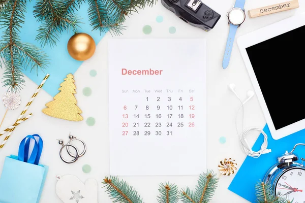 Página de calendário de dezembro, câmera digital, bugigangas de chrismas, ramo de abeto, relógio de pulso, papel azul, bloco de madeira com inscrição de dezembro, isolado em branco — Fotografia de Stock