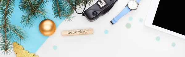 Панорамный снимок цифрового планшета, ель ветви, наручные часы, рождественские безделушки, деревянный блок с декабрьской надписью изолирован на белом — стоковое фото