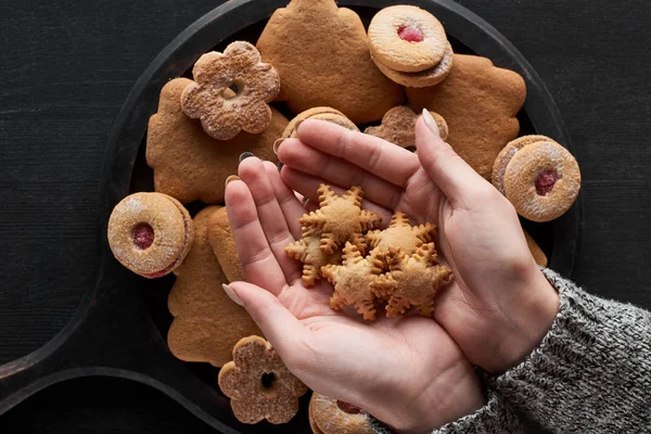 Vue partielle de la femme tenant des biscuits au flocon de neige dans les mains — Photo de stock