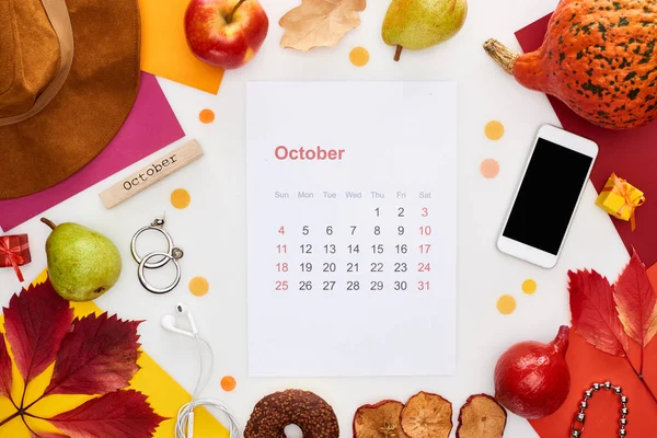 Página del calendario de octubre, sombrero, teléfono inteligente, frutas, calabaza, hojas secas, papeles multicolores, bloque de madera con inscripción de noviembre aislado en blanco - foto de stock
