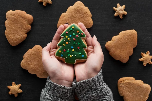 Cropped view of woman holding Christmas tree cookie in hands — Stock Photo