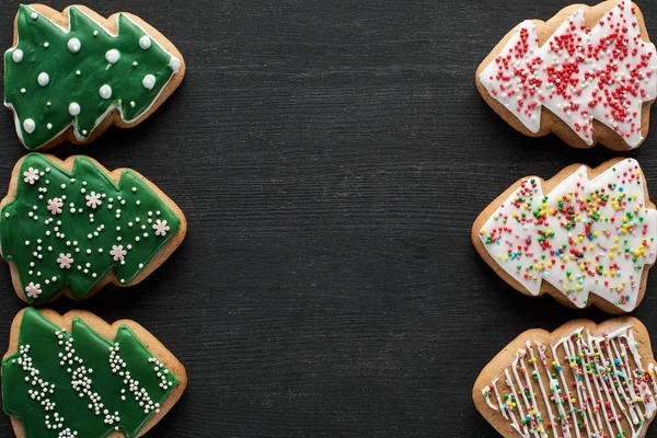 Flat lay with delicious glazed Christmas tree cookies on black background with copy space — Stock Photo
