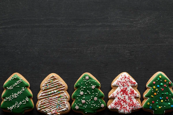 Flat lay with delicious glazed Christmas tree cookies on black background with copy space — Stock Photo