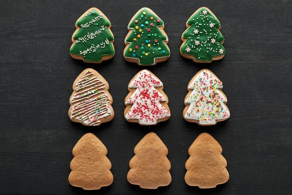 Flat lay with delicious glazed Christmas tree cookies on black background — Stock Photo