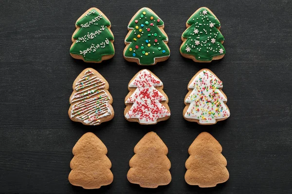 Flache Lage mit leckeren glasierten Christbaumkeksen auf schwarzem Hintergrund — Stockfoto