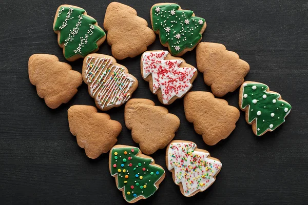 Flat lay with delicious Christmas tree cookies on black background — Stock Photo