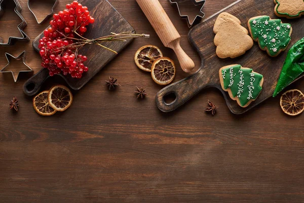 Top view of Christmas cookies near viburnum and spices on wooden table — Stock Photo