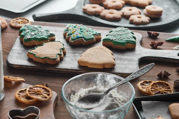 Selective focus of baked Christmas cookies near ingredients on wooden table — Stock Photo