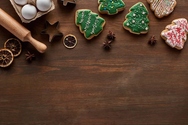 Top view of Christmas tree cookies, dough molds, eggs and rolling pin on wooden table — Stock Photo