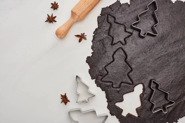 Vue du dessus de la pâte crue pour biscuits de Noël au chocolat sur fond blanc près de l'anis et du rouleau à pâtisserie — Photo de stock