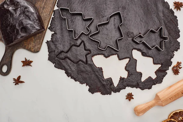 Vista dall'alto della pasta cruda per biscotti di Natale al cioccolato su sfondo bianco vicino all'anice e al mattarello — Foto stock