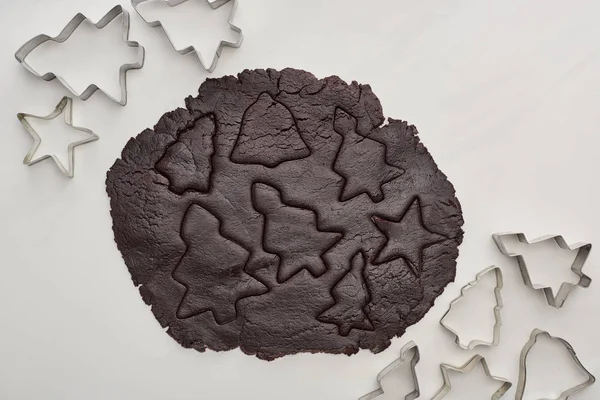 Vue du dessus de la pâte crue pour les biscuits de Noël au chocolat sur fond blanc près des moules à pâte — Photo de stock