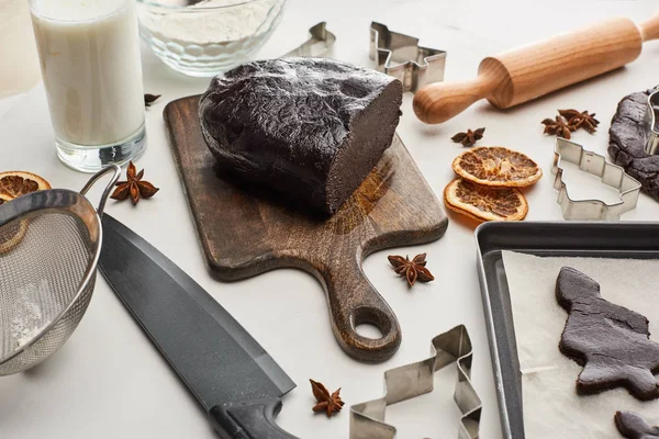 Roher Teig für Schokolade-Weihnachtskekse auf Holzschneidebrett in der Nähe frischer Zutaten auf weißem Hintergrund — Stockfoto