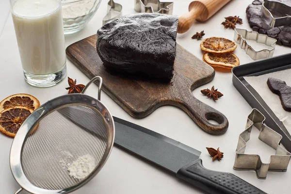 Raw dough for chocolate Christmas cookies on wooden cutting board near ingredients on white background — Stock Photo