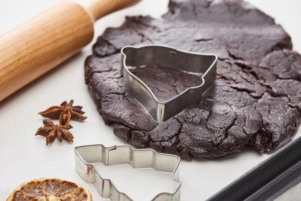 Pasta cruda per biscotti di Natale al cioccolato vicino mattarello e stampi per pasta su sfondo bianco — Foto stock