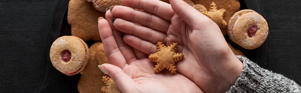 Vue recadrée de la femme tenant un cookie de flocon de neige dans les mains, vue panoramique — Photo de stock