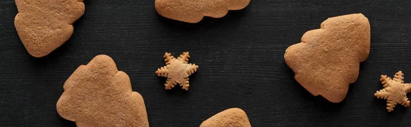 Top view of snowflake and Christmas tree cookies on black wooden table, panoramic shot — Stock Photo