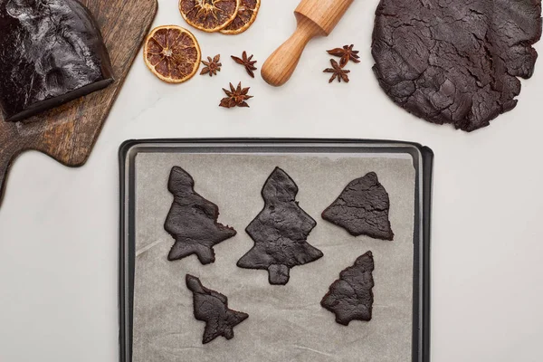 Vista superior de la masa cruda para galletas de Navidad cerca de la bandeja del horno sobre fondo blanco - foto de stock