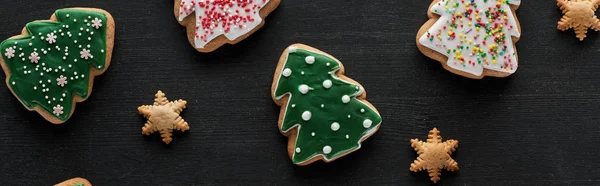 Delicious glazed Christmas cookies on black background, panoramic shot — Stock Photo