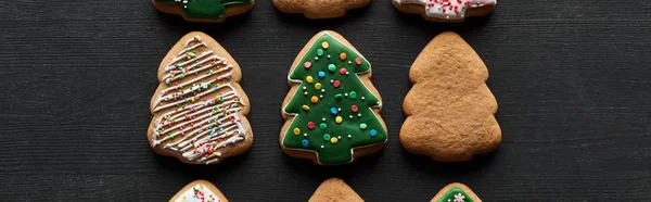 Plat étendu avec délicieux biscuits de sapin de Noël glacés sur fond noir, vue panoramique — Photo de stock