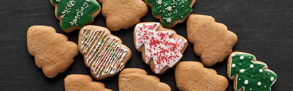 Flat lay with delicious glazed Christmas tree cookies on black background, panoramic shot — Stock Photo