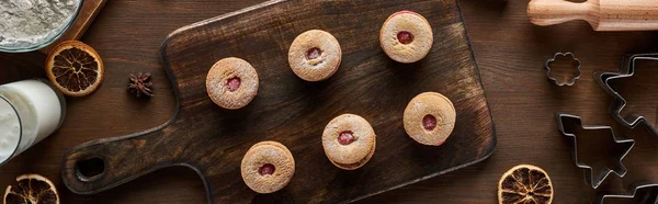 Draufsicht auf Weihnachtsplätzchen in der Nähe von Zutaten auf Holztisch, Panoramaaufnahme — Stockfoto