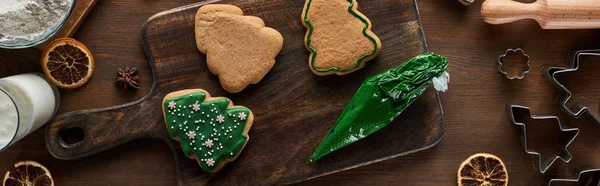 Vista dall'alto di biscotti natalizi smaltati con sacchetto di pasticceria su tavolo di legno, colpo panoramico — Foto stock