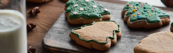 Selective focus of baked Christmas cookies near milk on wooden table, panoramic shot — Stock Photo