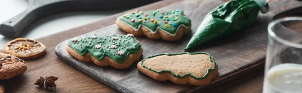 Fuoco selettivo di biscotti di Natale al forno vicino a sacchetto di pasticceria su tavolo di legno, colpo panoramico — Foto stock