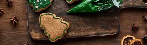 Vue de dessus des biscuits de sapin de Noël, sac à pâtisserie et épices d'hiver sur table en bois, vue panoramique — Photo de stock