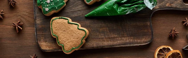 Top view of Christmas tree cookies, pastry bag and winter spices on wooden table, panoramic shot — Stock Photo