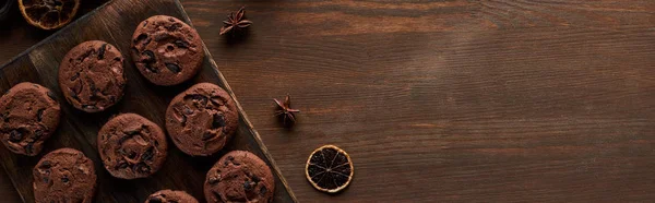 Vista superior de biscoitos de chocolate e especiarias em mesa de madeira com espaço de cópia, tiro panorâmico — Fotografia de Stock