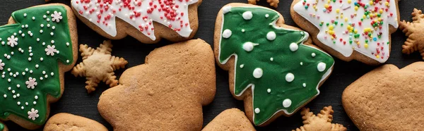 Delicious glazed Christmas cookies on black background, panoramic shot — Stock Photo