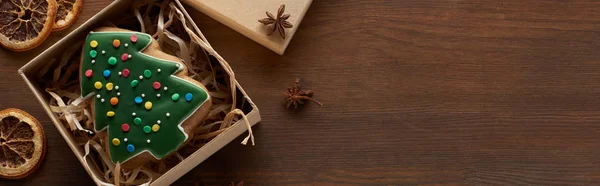 Vista dall'alto del biscotto dell'albero di Natale in scatola vicino agli agrumi secchi e anice al tavolo di legno, colpo panoramico — Foto stock