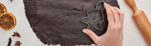 Cropped view of woman holding Christmas tree dough mold on raw dough on white background, panoramic shot — Stock Photo