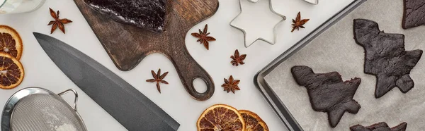 Vista dall'alto dei biscotti crudi dell'albero di Natale sul vassoio del forno vicino alle spezie invernali, stampi per coltello e pasta, colpo panoramico — Foto stock