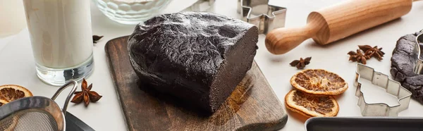 Pasta cruda per biscotti di Natale al cioccolato su tagliere di legno vicino a ingredienti su sfondo bianco, colpo panoramico — Foto stock